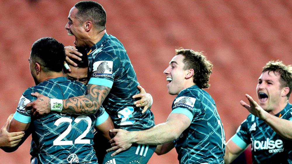 El medio scrum All Black Aaron Smith, en la cumbre del grupo de Highlanders que festeja victoria ante los Chiefs