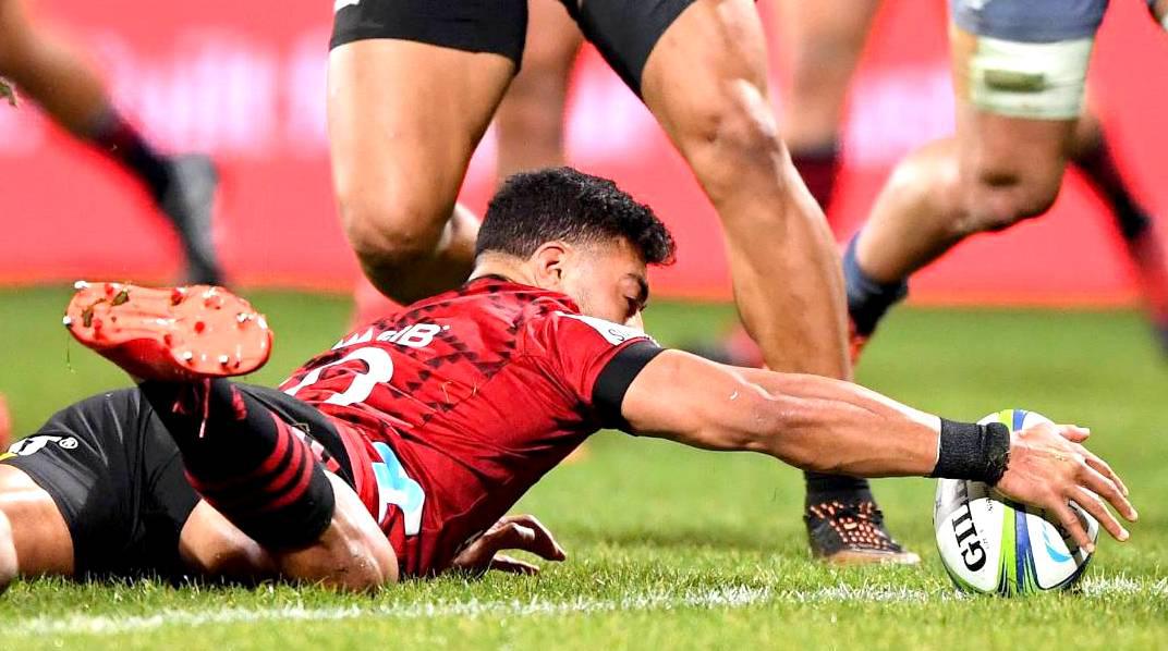 El apertura All Black Richie Mo'unga, se zambulle para marcar el try de los Crusaders ante los Hurricanes encendiendo pasiones en el estadio Orangetheory.