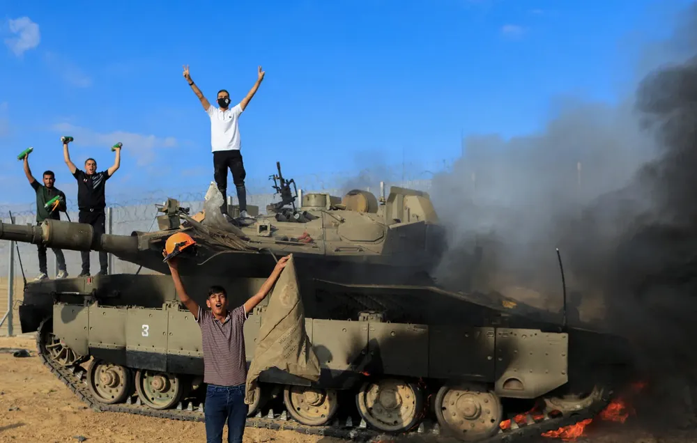 Los palestinos celebran mientras un vehículo militar israelí arde después de ser atacado por hombres armados palestinos